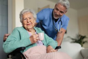 Older adult and family member compare care expenses at a kitchen table beside home documents.